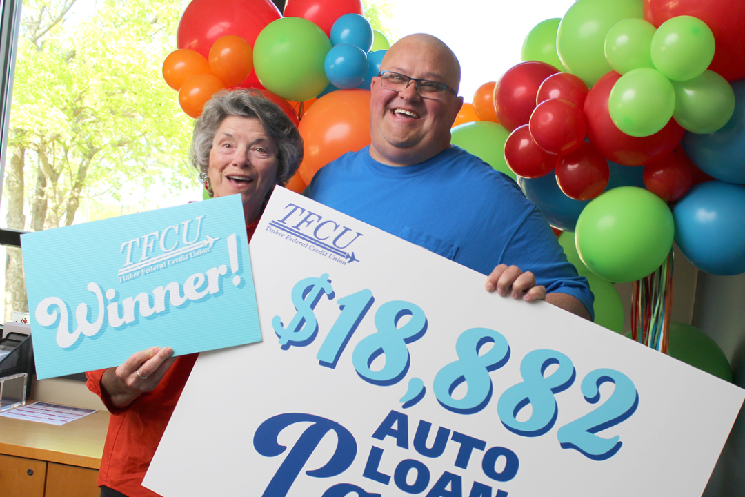 A man and his mom holding up signs that says winner and $18,882 auto loan payoff.