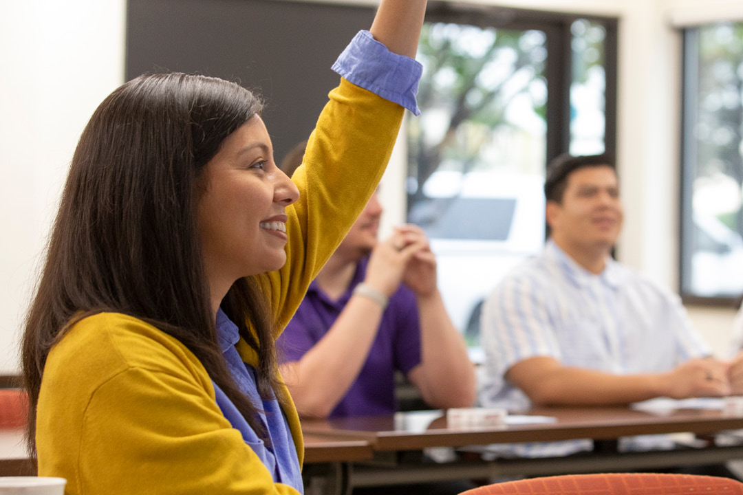 A woman raising her hand in a classroom setting.
