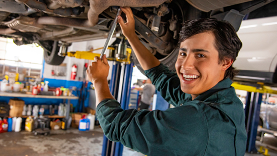 Young man working under a car in a workshop.