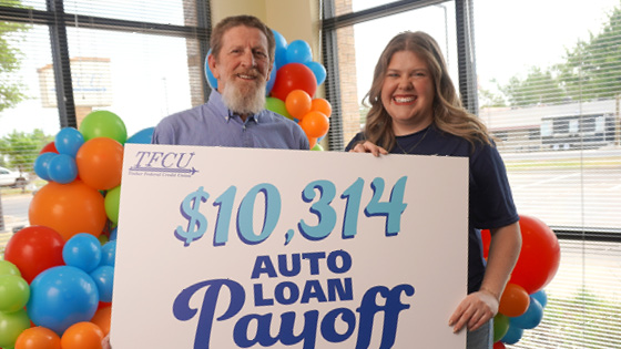 A man and TFCU employee holding up a sign that says $10,314 auto loan payoff.