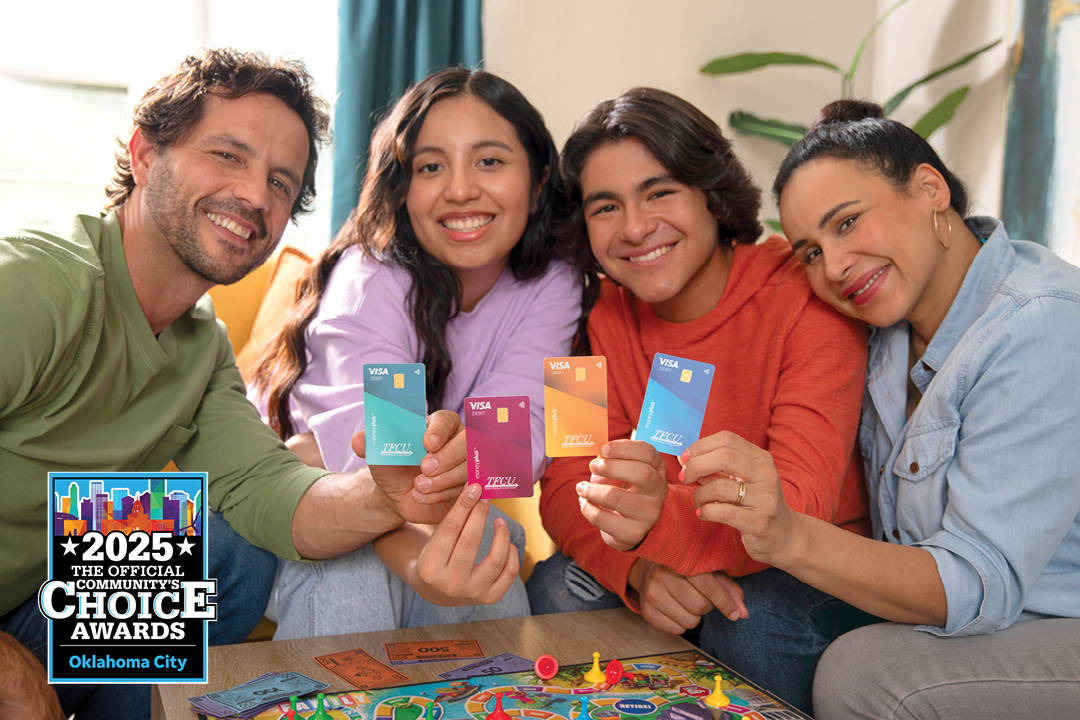 A family of four looking at the camera and smiling while holding up MoneyPlus cards