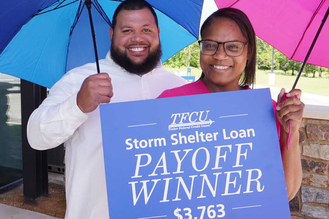 A couple holding umbrellas and a sign that says storm shelter loan payoff winner