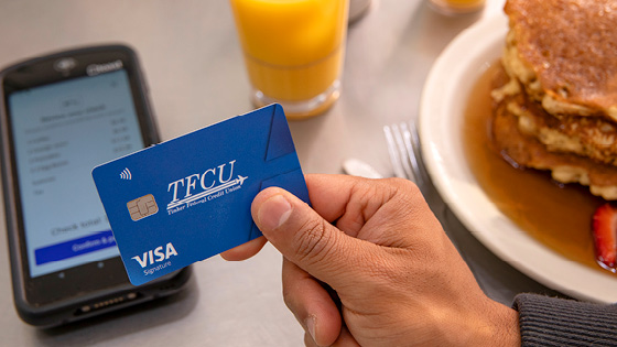 Paying tap with the Visa Signature card with pancakes and orange juice in the background.