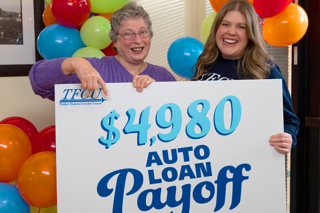 A TFCU member and TFCU employee holding a sign that says $4,980 auto loan payoff.