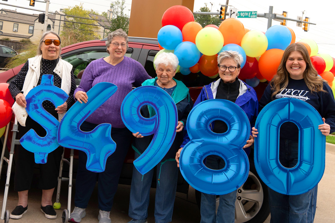 A group of people holding up number signs that reads $4,980.