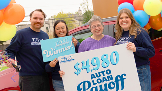 A group of TFCU employees standing with an auto loan payoff.