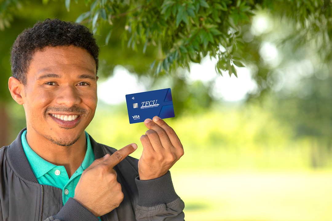A man holding up a blue TFCU credit card.