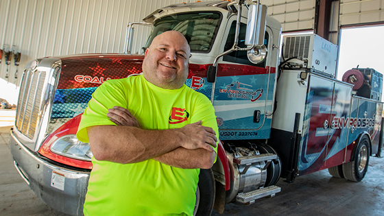 A man stands in front of a tractor trailer truck
