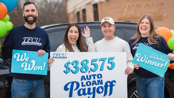 A man and woman hold a sign that says $38,575 Auto Loan Payoff with two TFCU employees