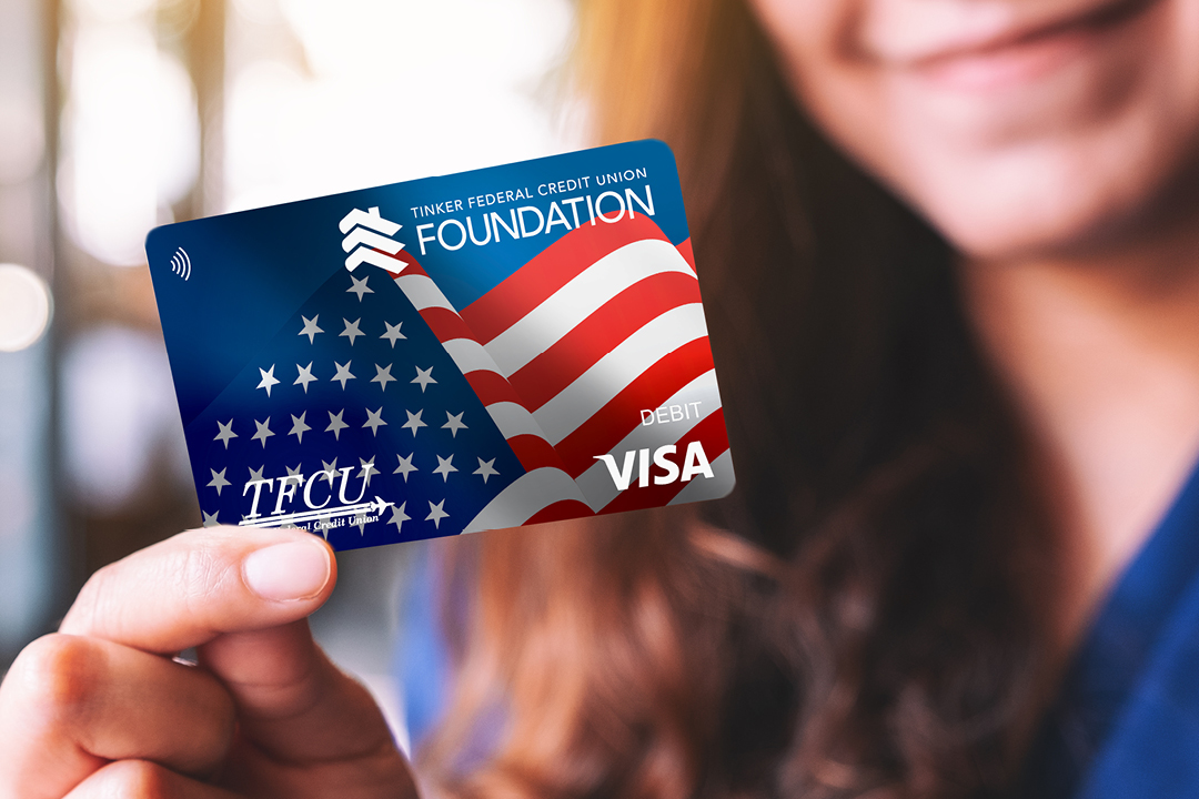 A woman holds up the TFCU Foundation Debit Card