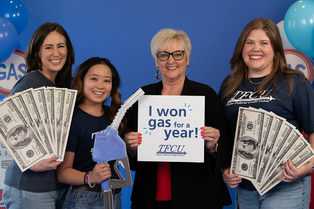 A woman stands with three TFCU employees and holds up a sign that says "I won gas for a year"