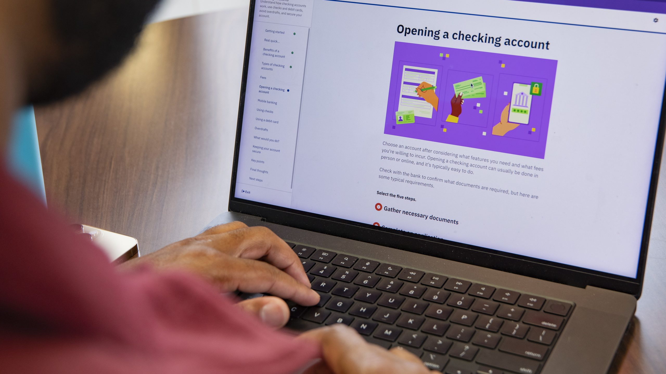 A man has an e-learning module on his laptop about opening a checking account