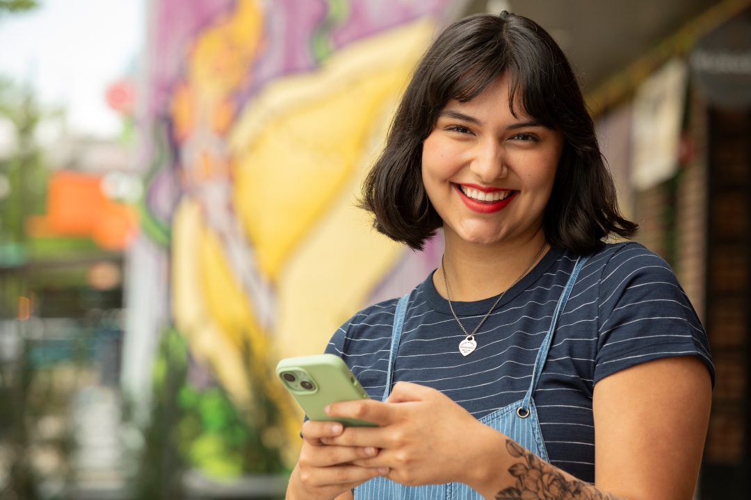 Young woman holding her mobile device and smiling.