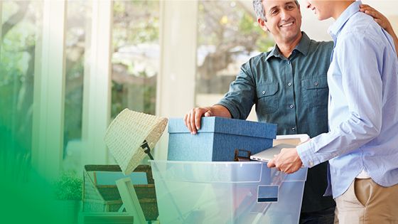 A man and woman holding a plastic bin full of varioius items.