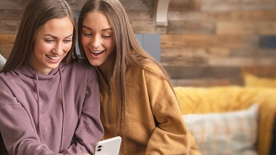 Two young ladies look at the same phone