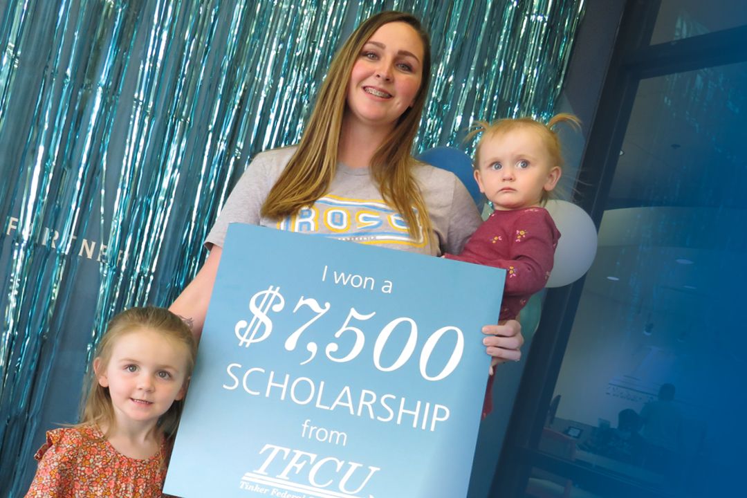 Evelyn Wing stands with children while holding sign that says she won a $7,500 scholarship from TFCU