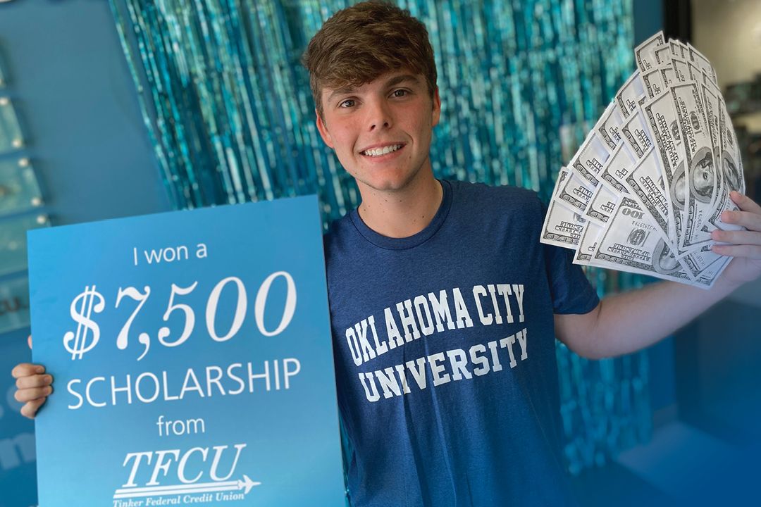 Jacob Wright holds sign showing he won a $7,500 scholarship from TFCU