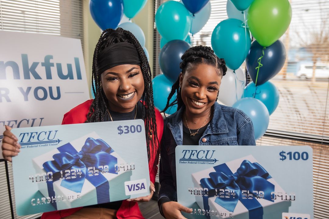 Two women holding gift card signs