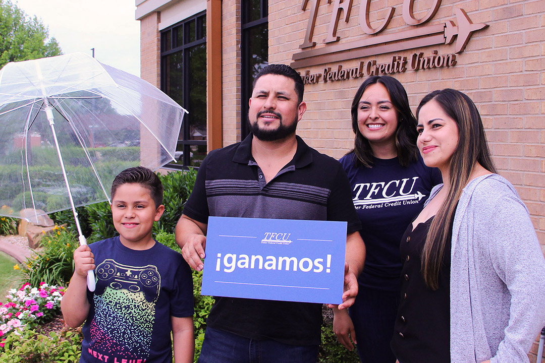 Family holding a winner's sign in front of building