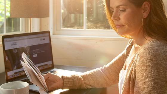 Woman looking at papers with a laptop