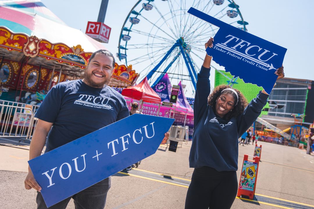 Two TFCU employees holding up signs that says TFCU.