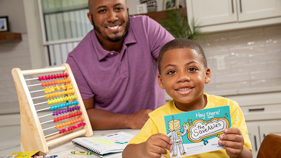 A dad with his son holding up a SaveAbles newsletter.