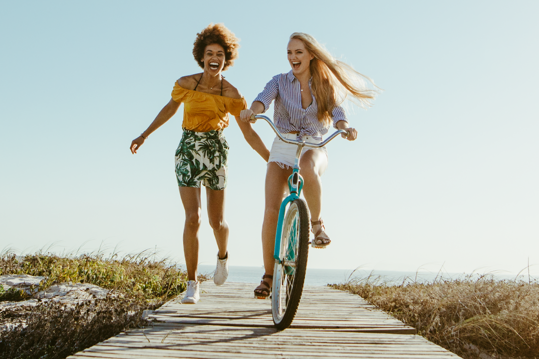 Two women outside with one on bike