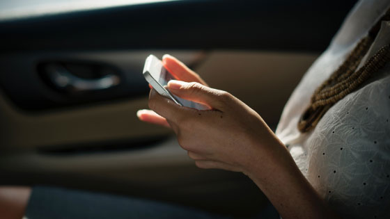 Close up of woman's hands on mobile device sitting in car.