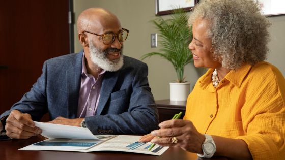 Two people sit together looking over paperwork