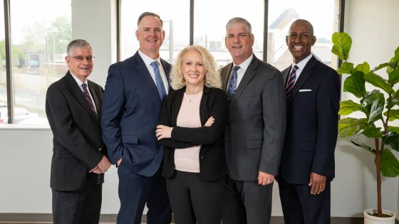 A group of business professionals stand in front of a window