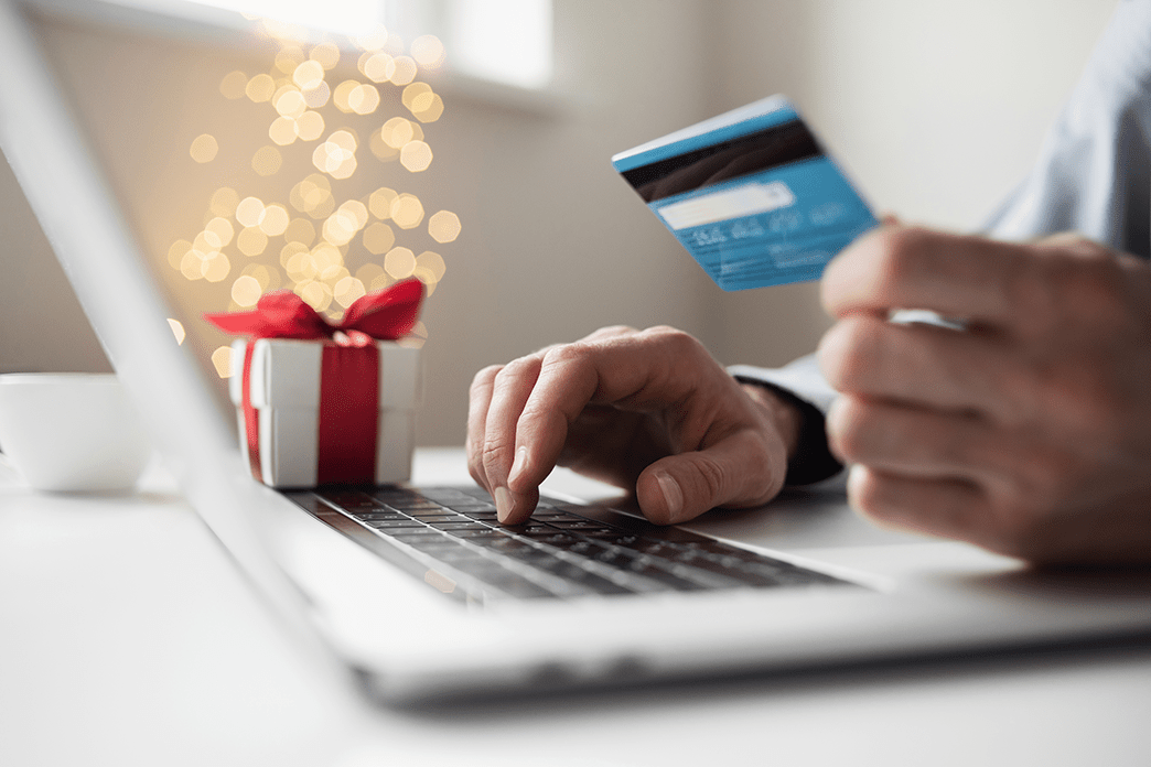 Close up of someone holding a card and on a laptop.