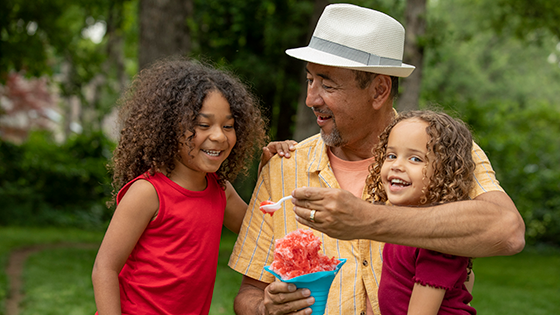 Grandpa with his two grandchildren eating a snowcone