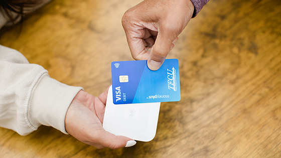 Close up of someone holding a moneyplus card to a contactless payment device