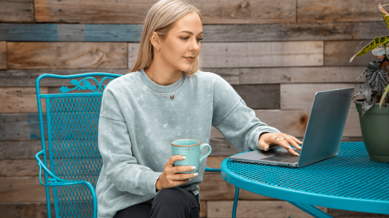 Woman on a laptop holding a mug.