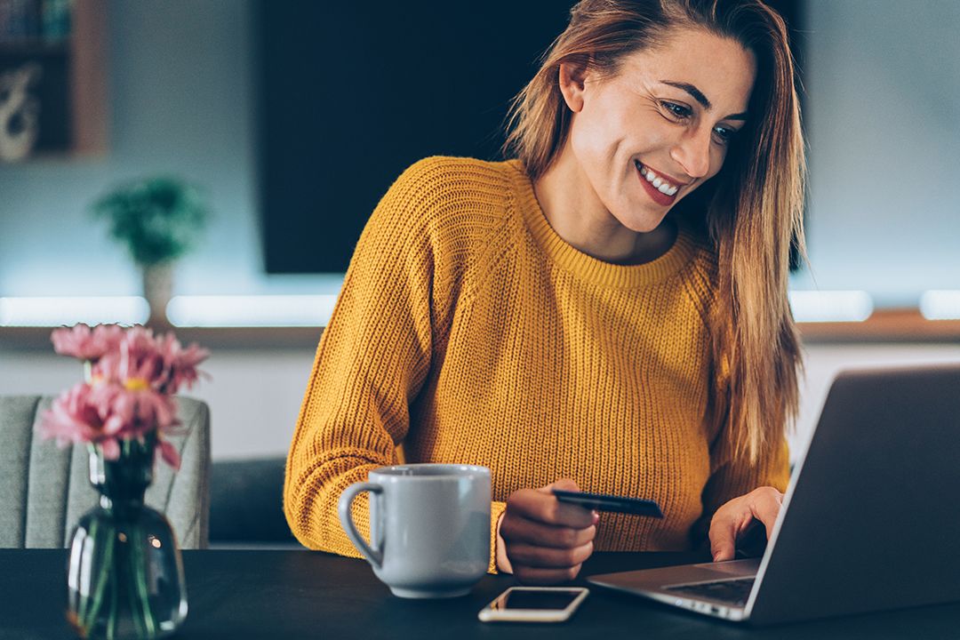 Young woman shopping online with credit card and lap top at home