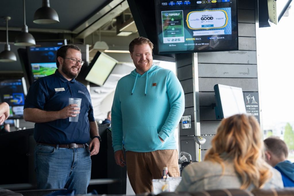 A TFCU employee and man stand together at Top Golf